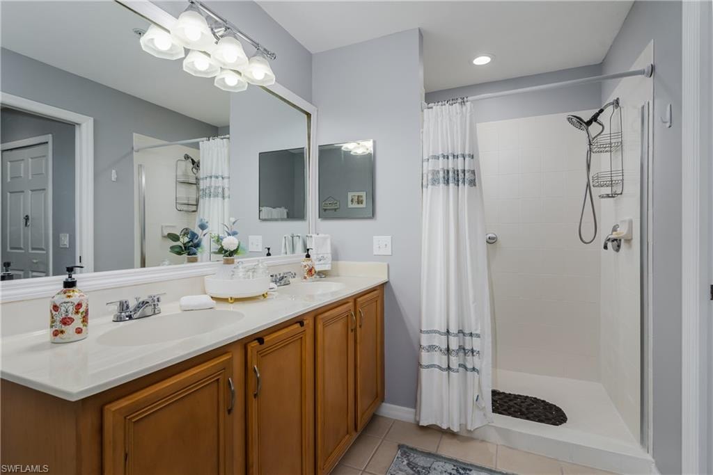 Full bathroom with double vanity, a shower stall, and light tile patterned floors