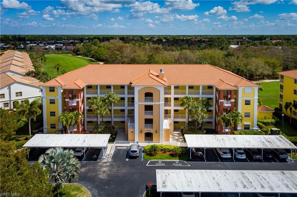 View of apartment building / complex featuring covered parking and golf course view
