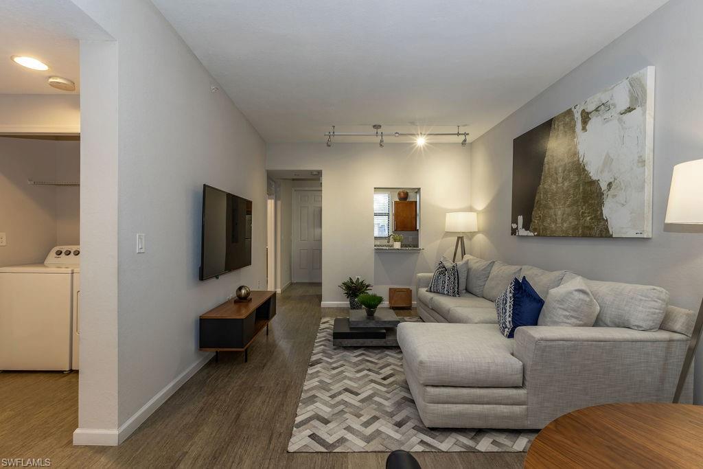 Living room with wood finished floors, rail lighting, and washer and dryer