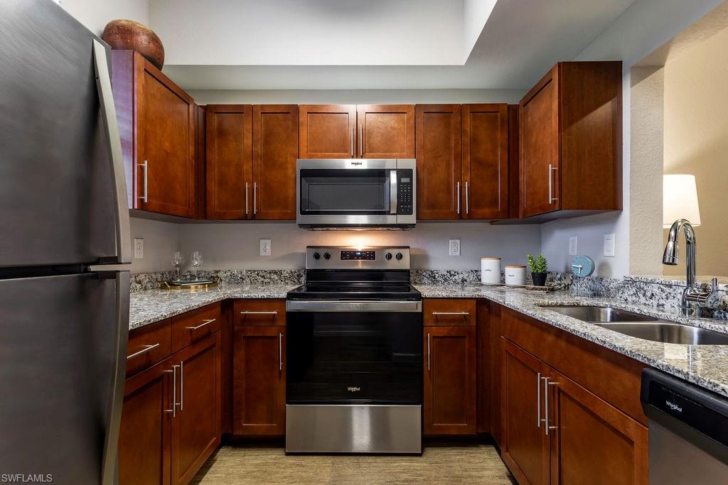 Kitchen with stainless steel appliances and light stone counters
