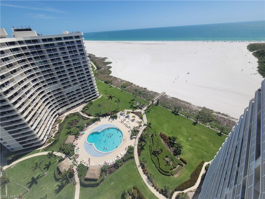 Birds eye view of property with a water view and a beach view
