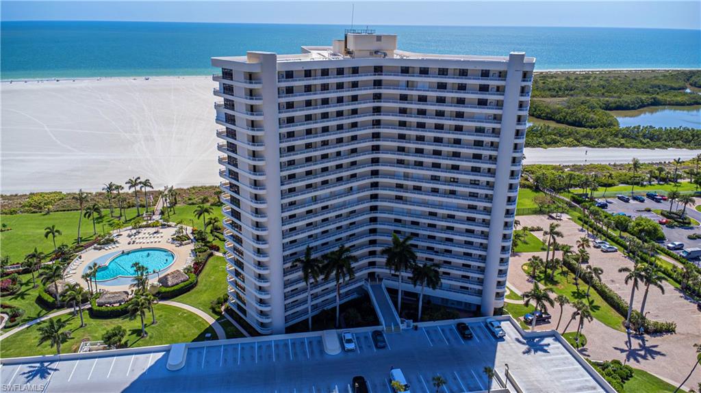 View of building exterior with a community pool, a beach view, and a water view