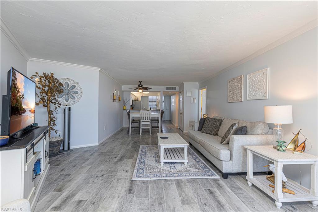 Living room with ceiling fan, hardwood / wood-style floors, and crown molding