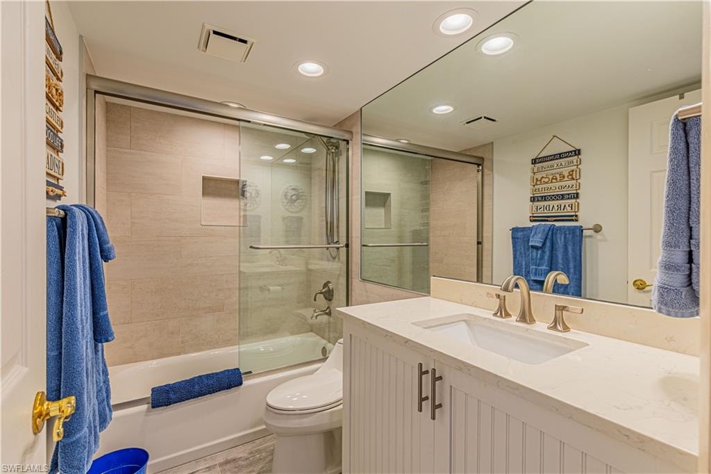 Full bathroom featuring toilet, vanity, and combined bath / shower with glass door