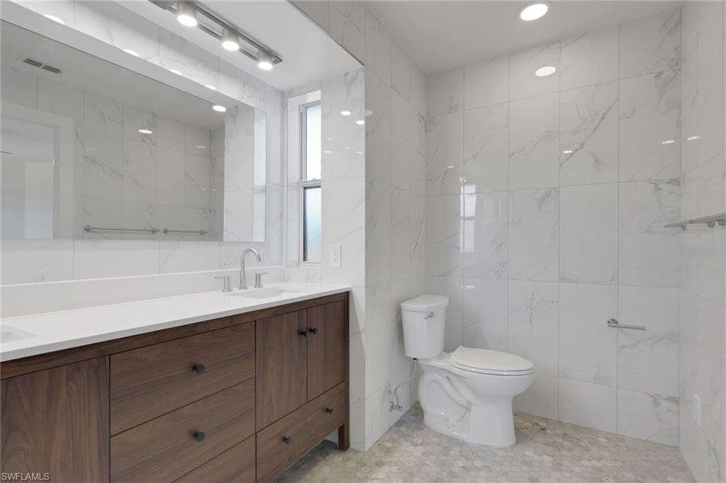 Full bath featuring tile walls and double vanity