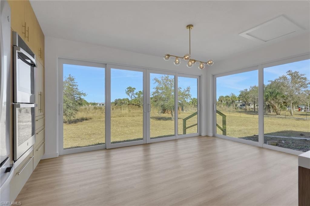 Unfurnished sunroom with plenty of natural light and a chandelier