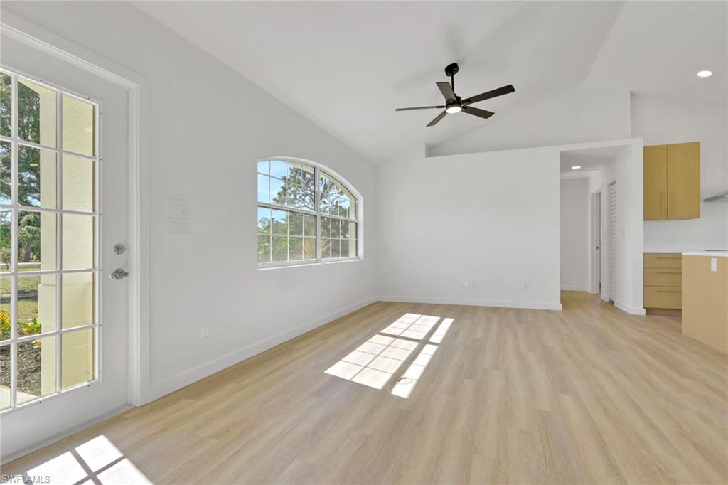 Unfurnished living room with light wood finished floors, vaulted ceiling, and ceiling fan