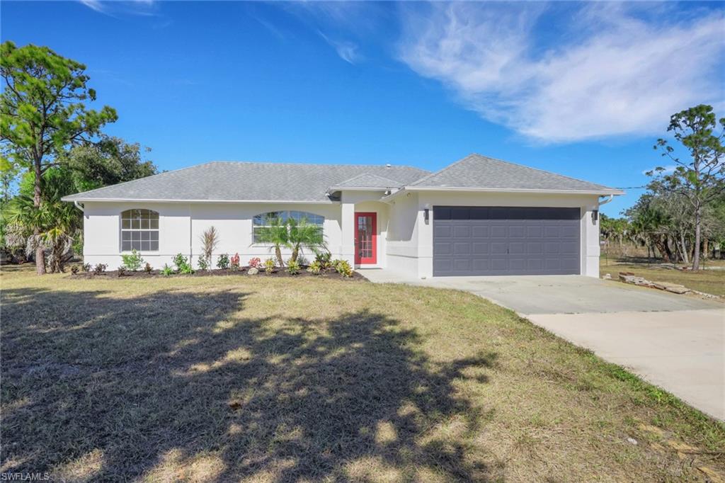 Ranch-style house featuring a front lawn, stucco siding, driveway, a garage, and roof with shingles