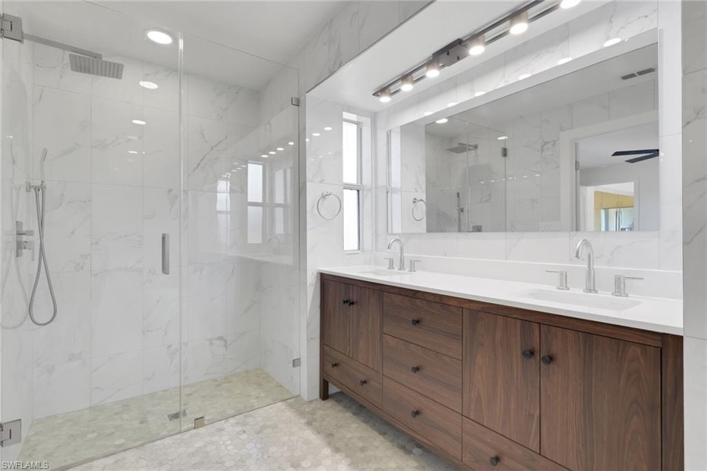 Bathroom with double vanity, a marble finish shower, and recessed lighting