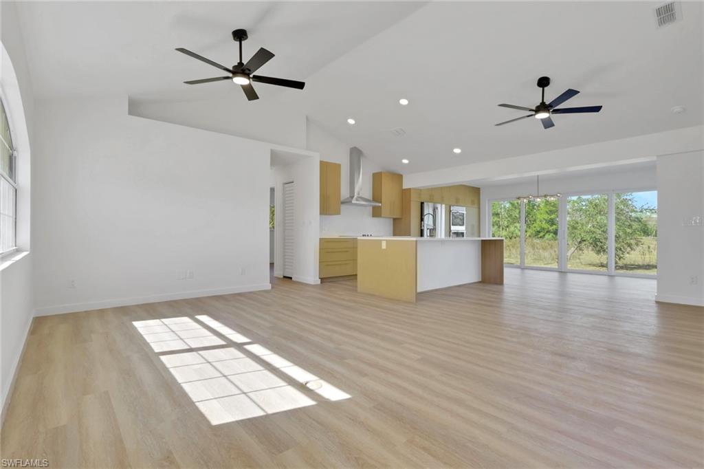 Unfurnished living room featuring a ceiling fan, light wood-style flooring, recessed lighting, and high vaulted ceiling