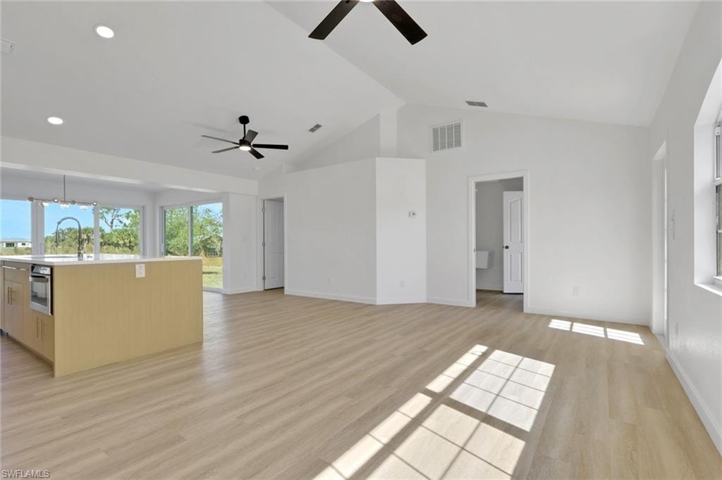 Unfurnished living room featuring light wood finished floors and high vaulted ceiling
