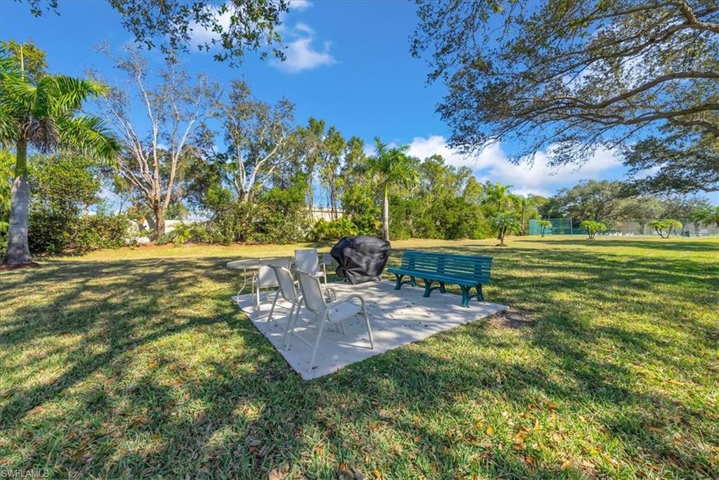 View of green lawn featuring a patio area and view of scattered trees