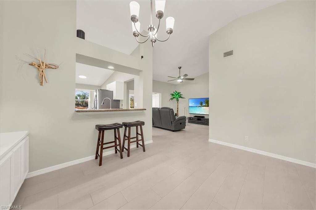 Dining area featuring a chandelier, high vaulted ceiling, light wood finished floors, and ceiling fan