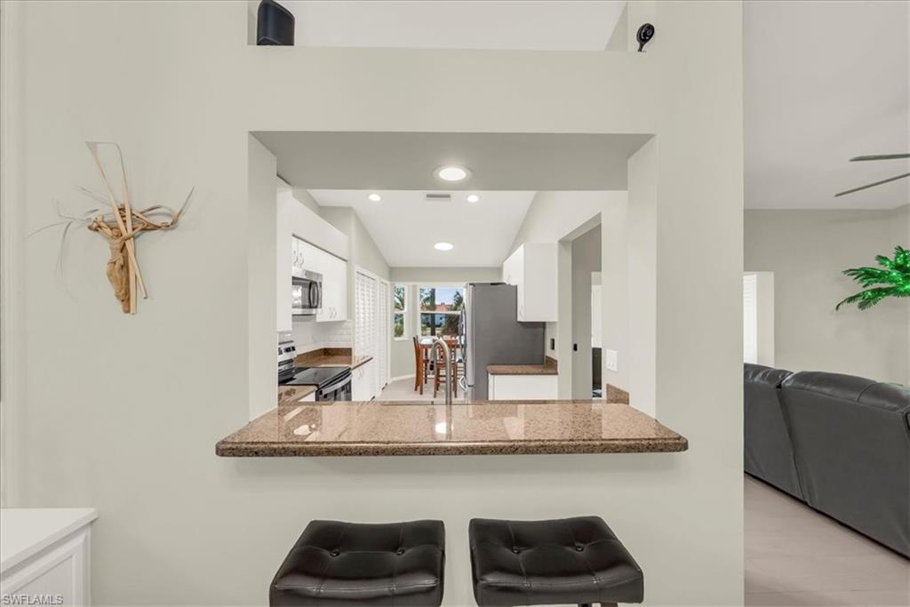 Kitchen featuring white cabinets, stainless steel appliances, recessed lighting, open floor plan, and a kitchen breakfast bar