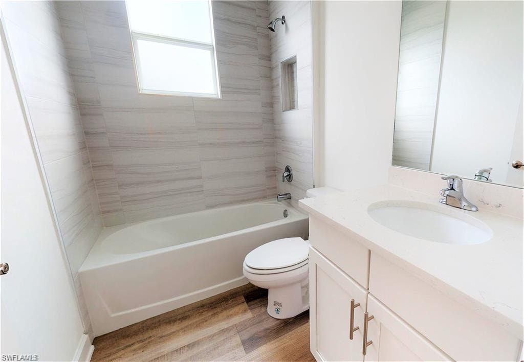 Full bath featuring shower / tub combination, vanity, and light wood-style flooring