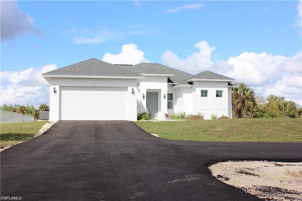 View of front of property with stucco siding, roof with shingles, asphalt driveway, and a garage