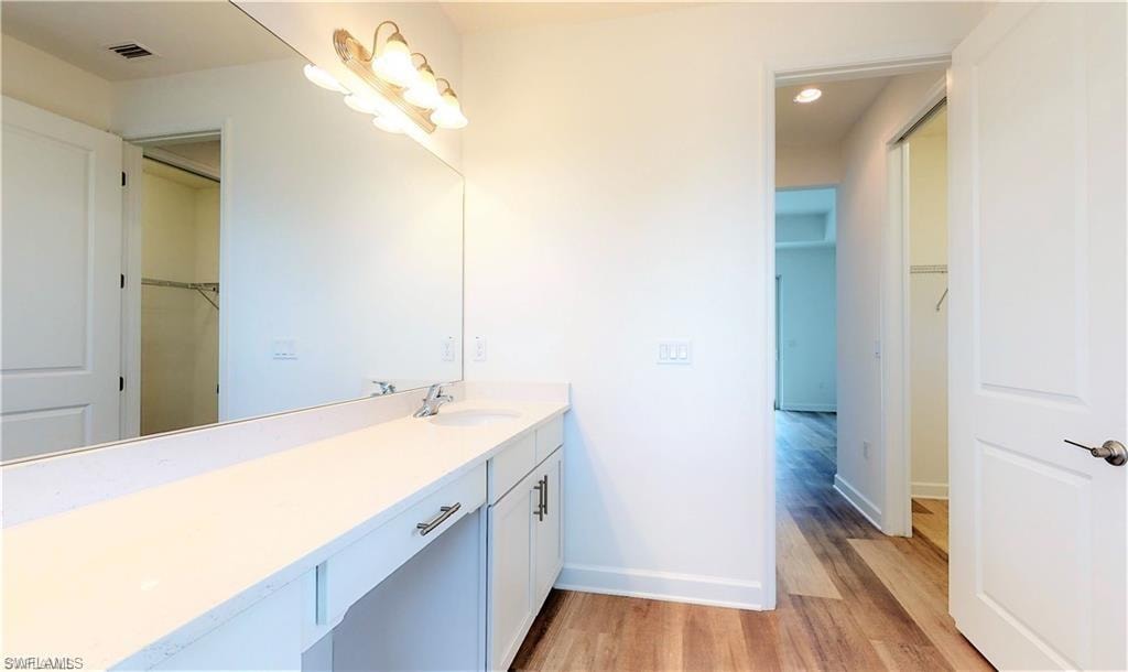 Full bath, vanity, light wood-type flooring, and recessed lighting