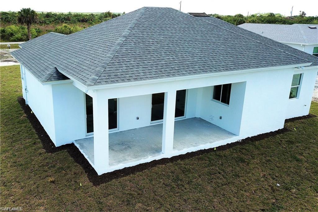 Back of house with a yard, stucco siding, a patio area, and roof with shingles