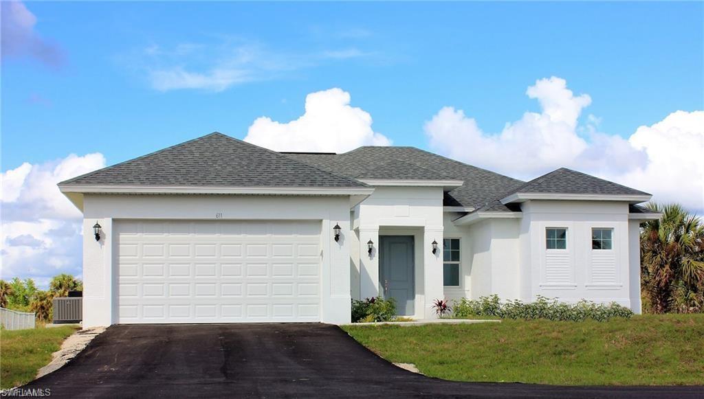 View of front of home with a shingled roof, stucco siding, a front lawn, asphalt driveway, and a garage