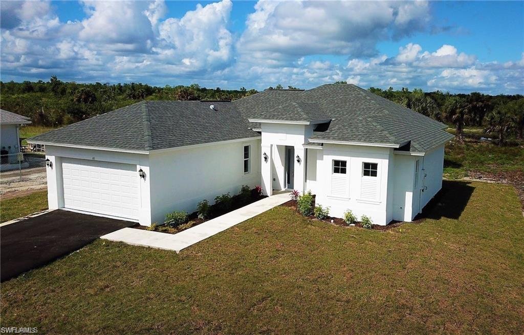 View of front of house with stucco siding, an attached garage, roof with shingles, and asphalt driveway