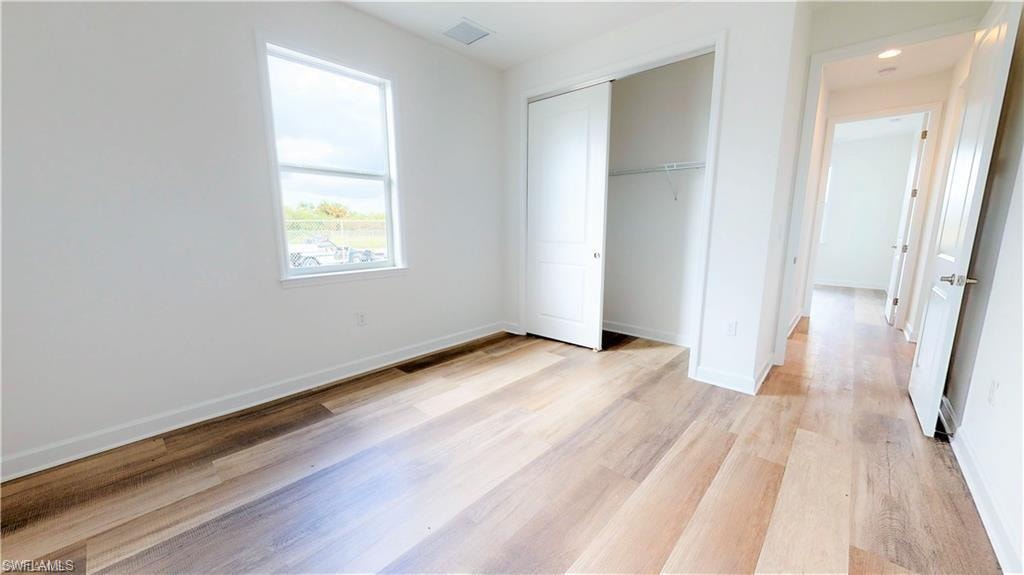 Unfurnished bedroom featuring light wood-style floors and a closet