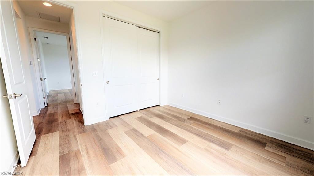 Unfurnished bedroom with a closet and light wood-type flooring