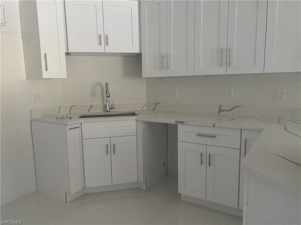 Kitchen featuring light stone countertops and white cabinets