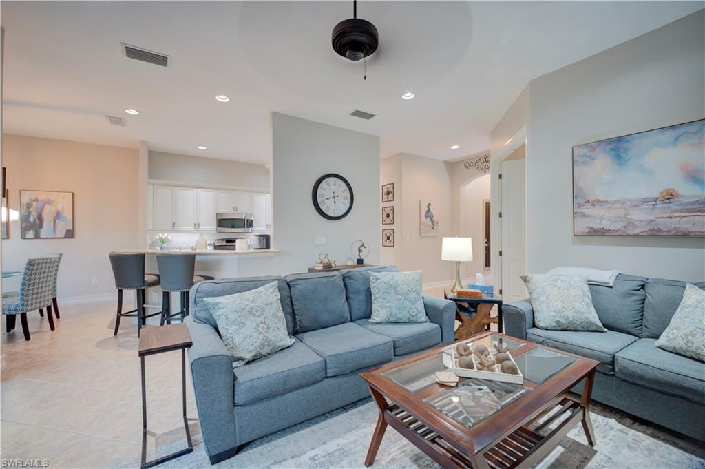 Living area featuring recessed lighting, ceiling fan, light tile patterned floors, and arched walkways