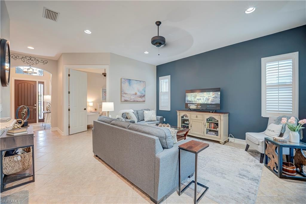 Living room with recessed lighting, arched walkways, ceiling fan, and light tile patterned floors
