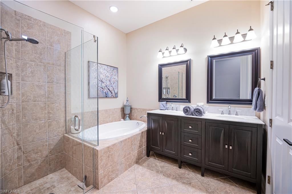 Bathroom featuring double vanity, a stall shower, a bath, light tile patterned flooring, and recessed lighting