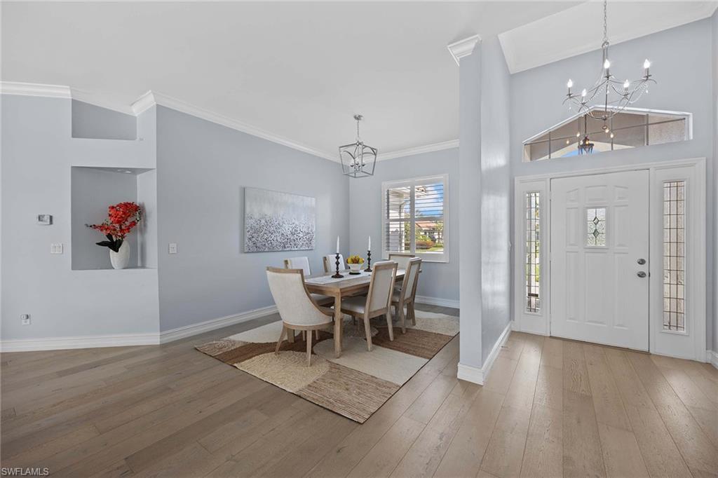 Entrance foyer featuring a chandelier, ornamental molding, and light wood-style floors