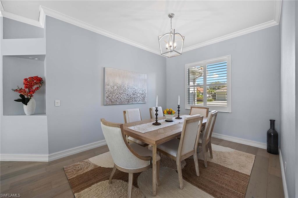 Dining space with ornamental molding, wood finished floors, and a chandelier