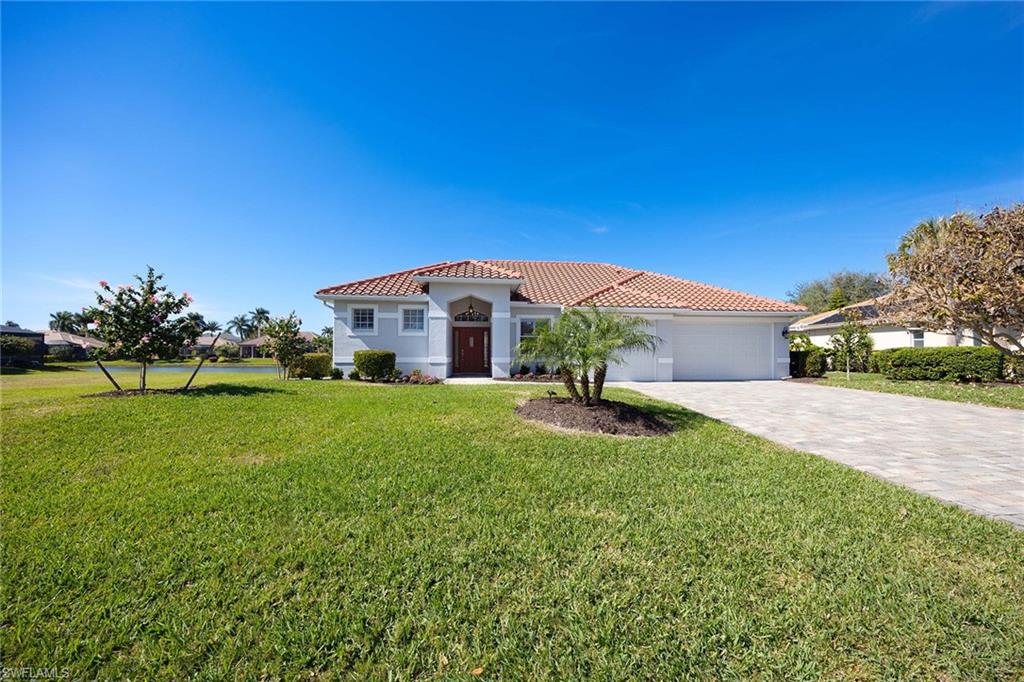 Mediterranean / spanish house with a tile roof, a front yard, stucco siding, decorative driveway, and a garage