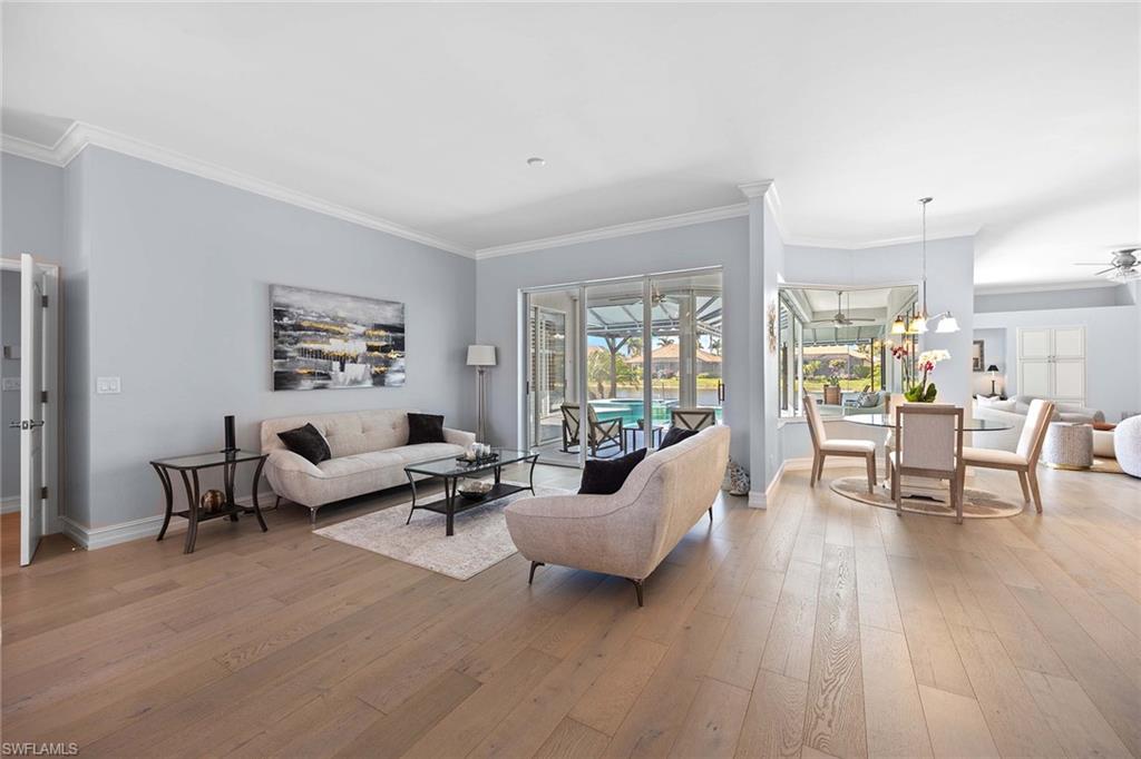 Living room with crown molding, light wood finished floors, and a ceiling fan