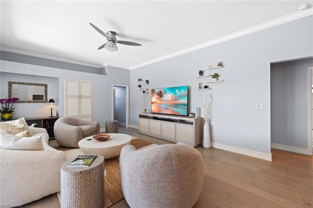 Living room with crown molding, a ceiling fan, and light wood-style floors