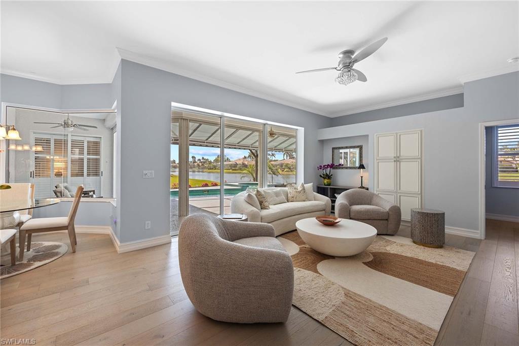 Living area with ceiling fan, crown molding, light wood-style floors, and healthy amount of natural light