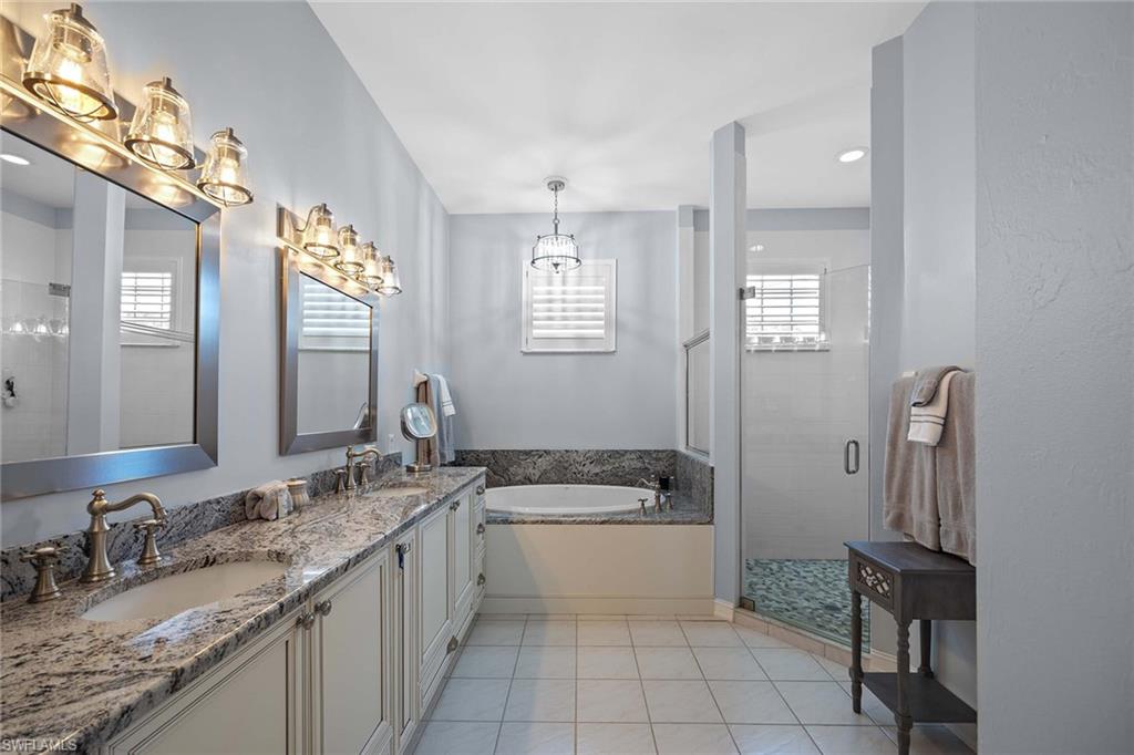 Bathroom featuring a stall shower, double vanity, a garden tub, light tile patterned floors, and recessed lighting