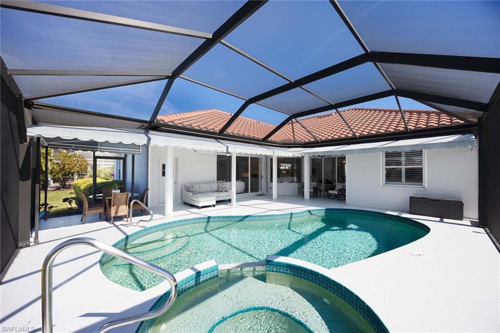 View of swimming pool featuring a pool with connected hot tub, a sunroom, glass enclosure, and a patio area
