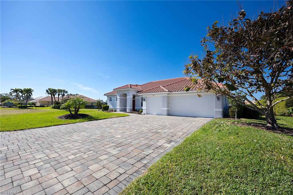 Mediterranean / spanish-style house featuring a front yard, an attached garage, decorative driveway, a tiled roof, and stucco siding