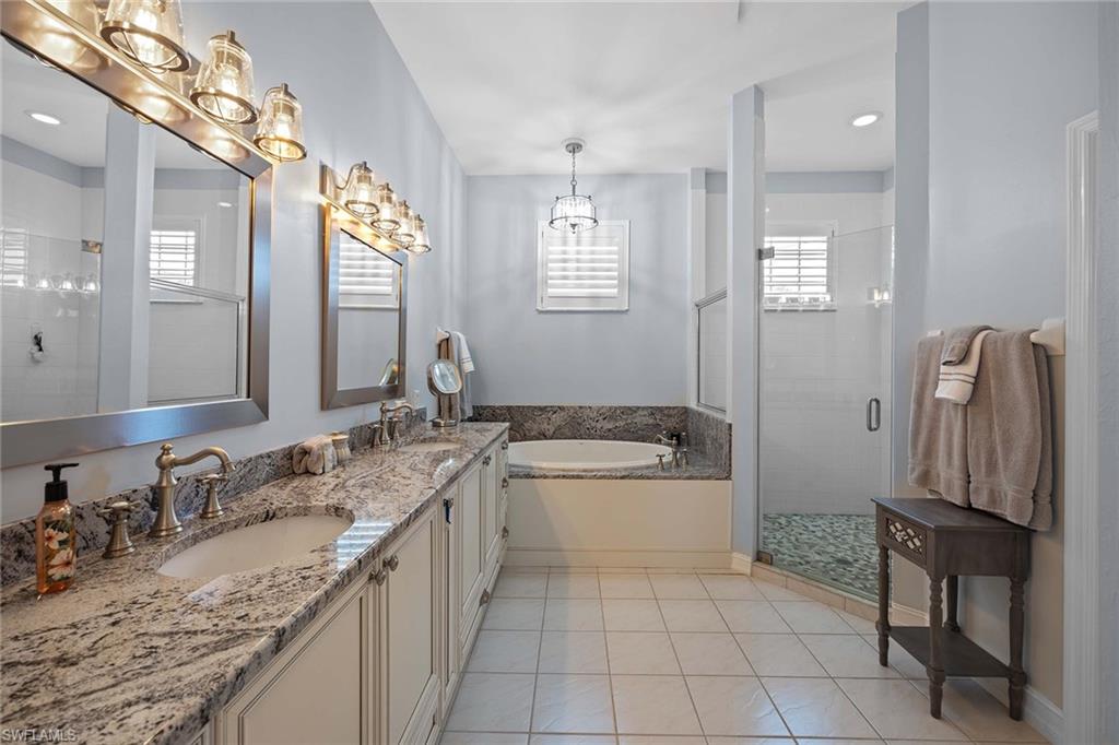 Full bath featuring a stall shower, double vanity, light tile patterned floors, a garden tub, and recessed lighting