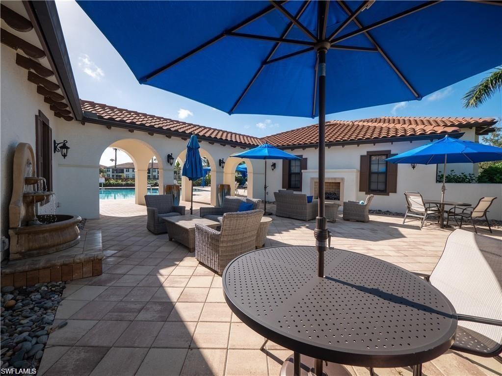 View of clubhouse patio with outdoor lounge area, fireplace, and the community pool.