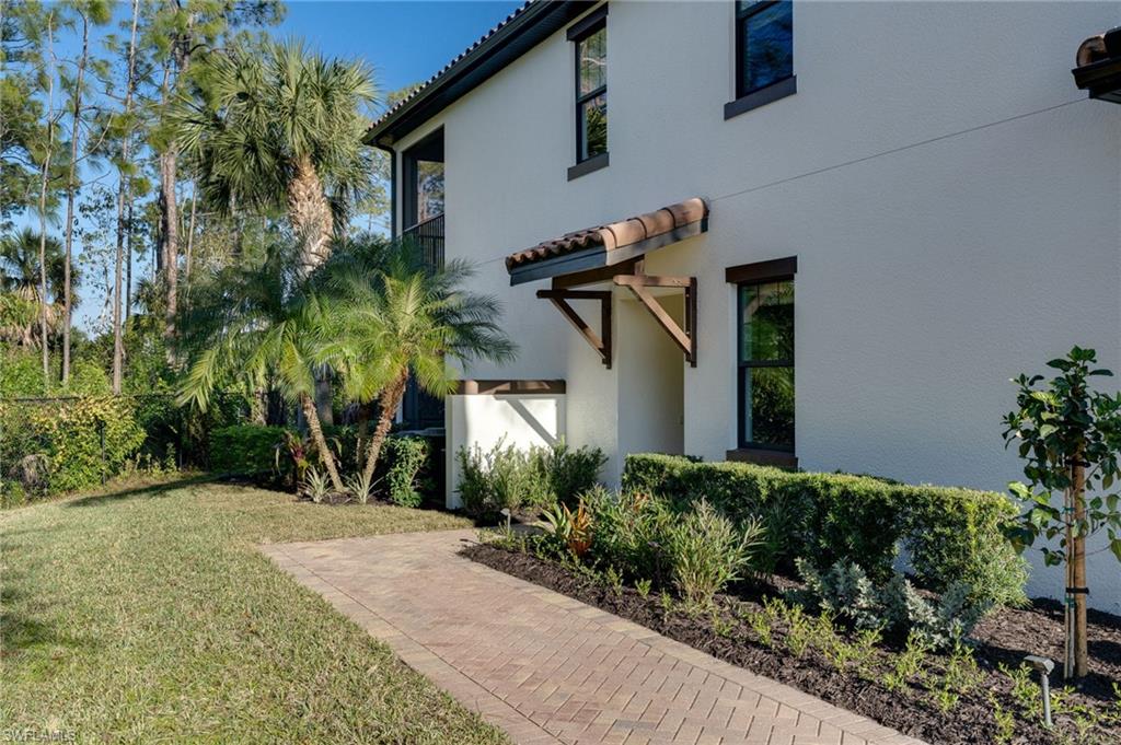 View of side of property featuring a lawn, a tile roof, and stucco siding