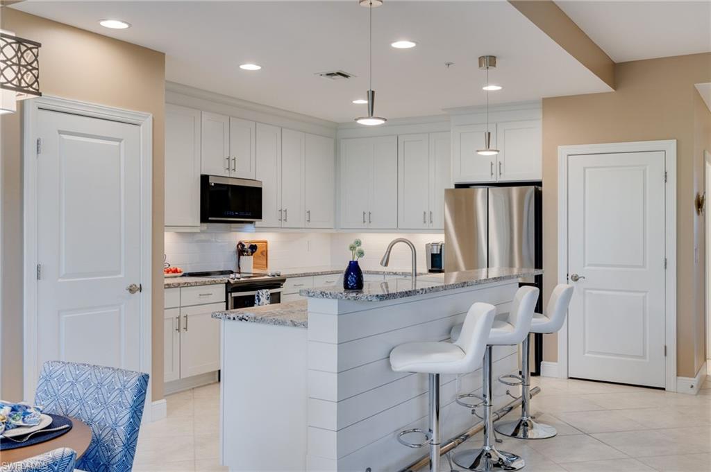 Kitchen with hanging light fixtures, white cabinets, a kitchen breakfast bar that features ship-lap and a custom foot rest.