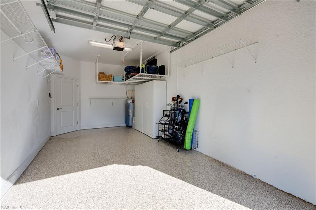 The garage, featuring an epoxy floor, lots of shelving, two ceiling-mounted storage racks, and two white metal cabinets measuring 32" x 72", will convey to the buyer.