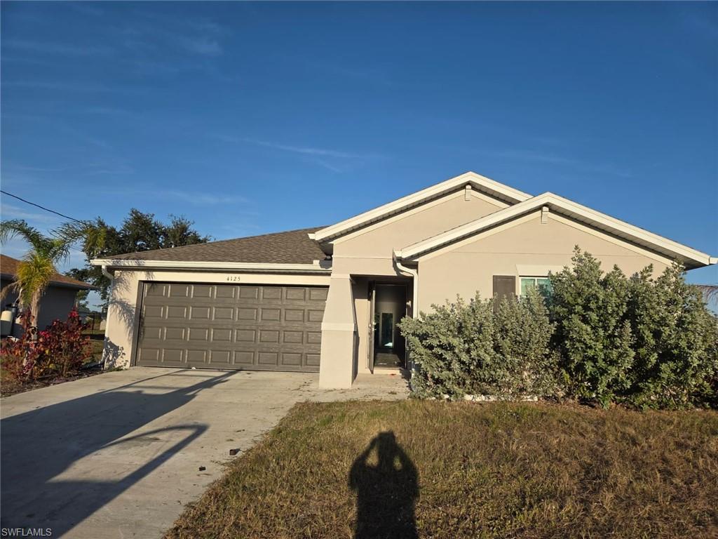 Single story home featuring stucco siding, concrete driveway, an attached garage, and roof with shingles