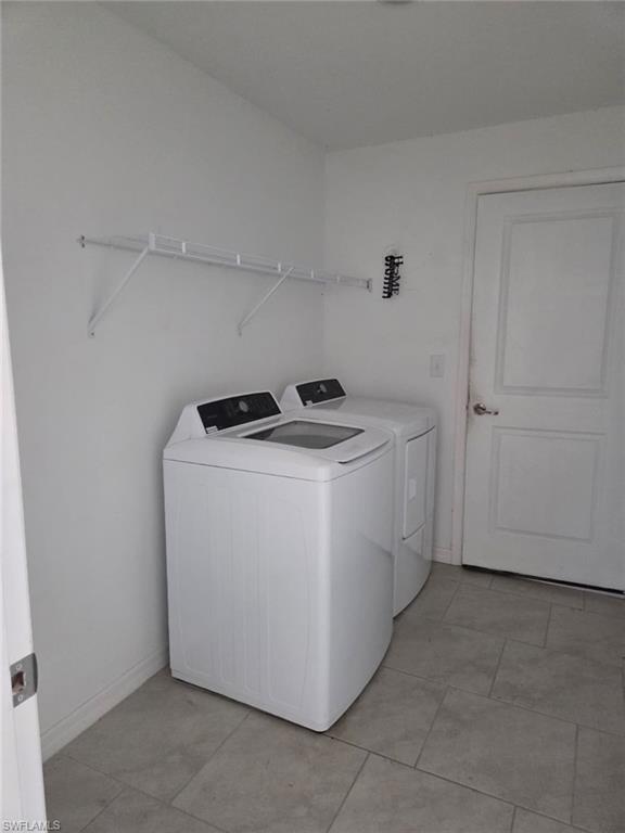 Laundry area with washing machine and clothes dryer and light tile patterned flooring