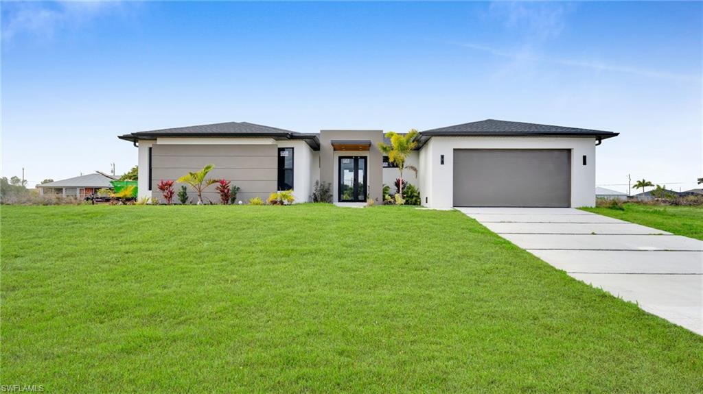Prairie-style house featuring a front lawn, driveway, and stucco siding