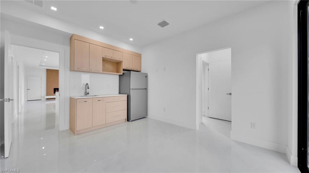 Kitchen with light brown cabinets, light countertops, freestanding refrigerator, recessed lighting, and modern cabinets