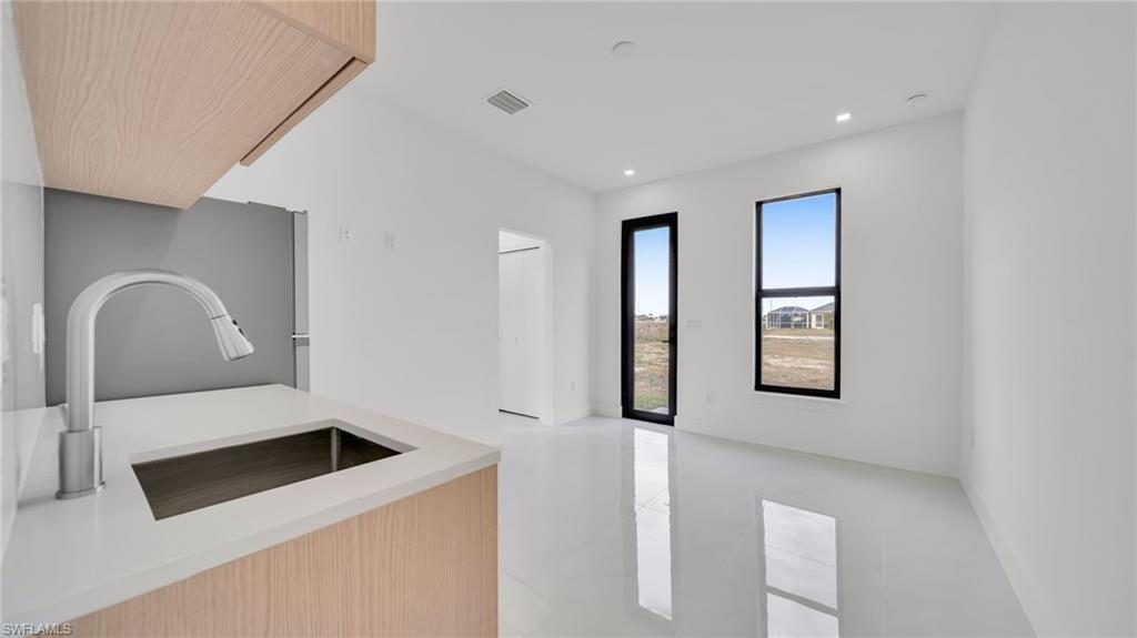 Kitchen featuring light brown cabinets, modern cabinets, light stone counters, and recessed lighting