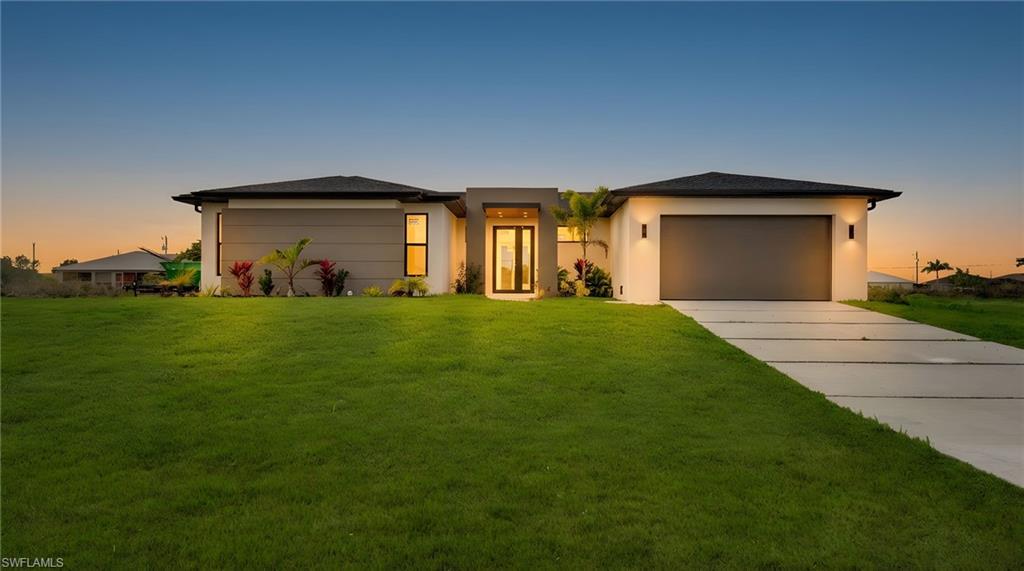 Prairie-style house with a yard, stucco siding, and concrete driveway